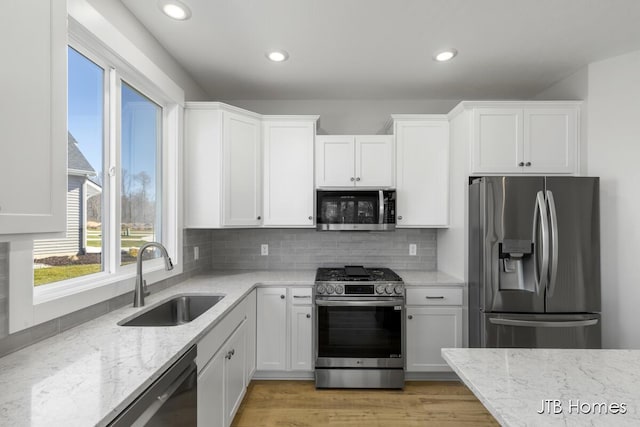 7571 Brook Villa Ct, Allendale, MI 49401 - kitchen featuring appliances with stainless steel finishes, a sink, light stone countertops, white cabinetry, and recessed lighting