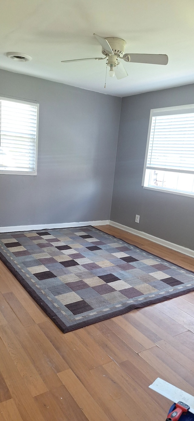 unfurnished room featuring baseboards, a ceiling fan, and wood finished floors