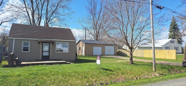 view of front facade featuring a detached garage, a shingled roof, an outdoor structure, fence, and a front yard