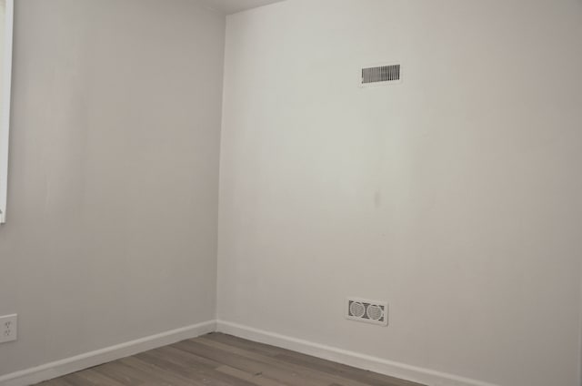 unfurnished room featuring baseboards, dark wood-type flooring, and visible vents