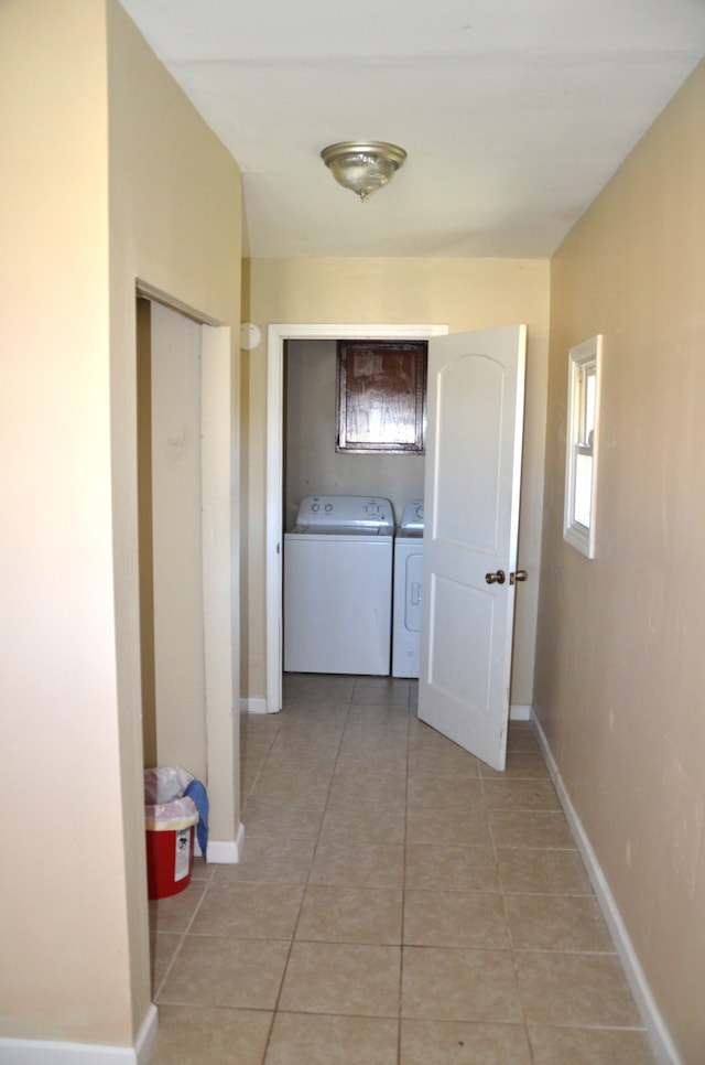 corridor with light tile patterned flooring, baseboards, and separate washer and dryer