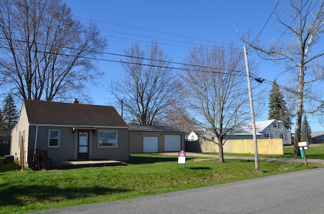 view of front facade featuring fence, a chimney, a front yard, and a detached garage