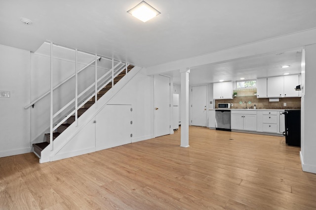 1657 Glenwood Rd, Ann Arbor, MI 48104 - unfurnished living room featuring light wood-style floors, stairway, baseboards, and a sink