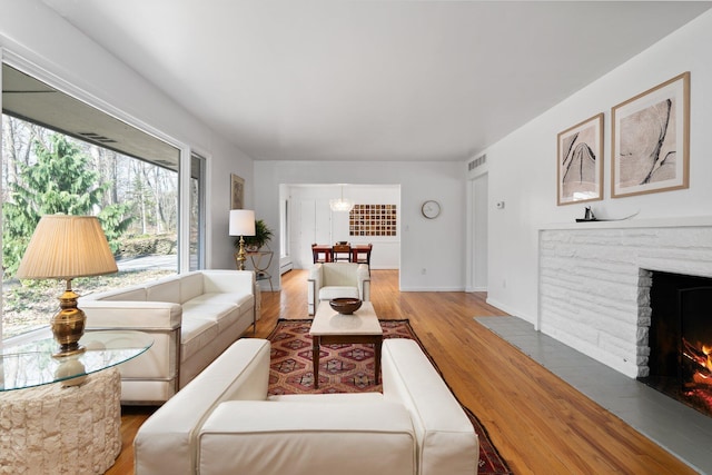 1657 Glenwood Rd, Ann Arbor, MI 48104 - living room with light wood-style floors, a brick fireplace, baseboards, and a baseboard radiator