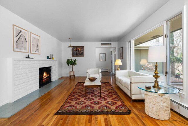 1657 Glenwood Rd, Ann Arbor, MI 48104 - living area featuring a baseboard radiator, wood-type flooring, and a lit fireplace