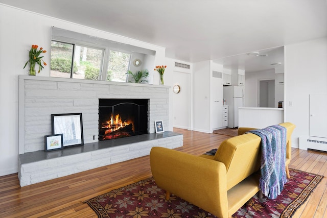 1657 Glenwood Rd, Ann Arbor, MI 48104 - living area with wood-type flooring, a lit fireplace, and baseboard heating