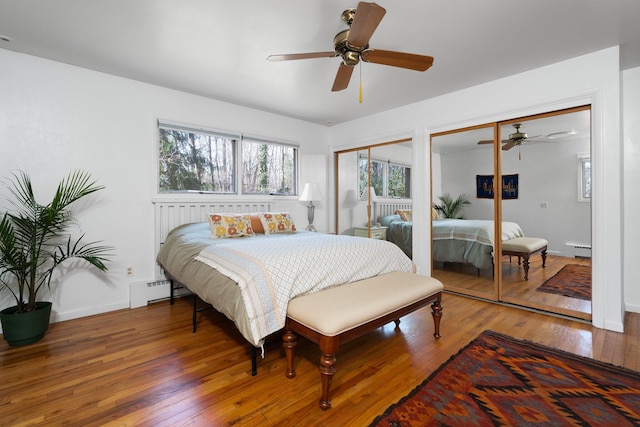 1657 Glenwood Rd, Ann Arbor, MI 48104 - bedroom featuring multiple closets, wood-type flooring, a baseboard radiator, baseboards, and ceiling fan