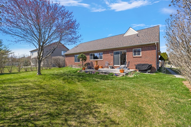 rear view of house featuring a patio area, brick siding, a yard, and roof with shingles