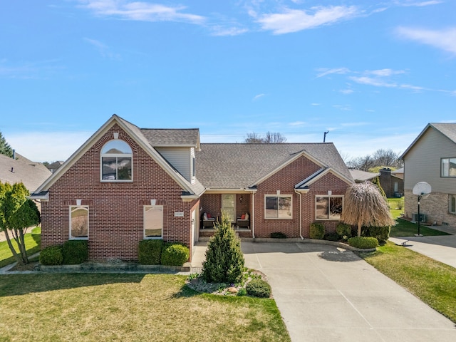 view of front of property with brick siding, roof with shingles, a front lawn, and concrete driveway