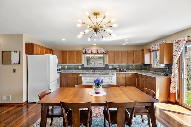kitchen featuring brown cabinetry, wood finished floors, visible vents, and freestanding refrigerator