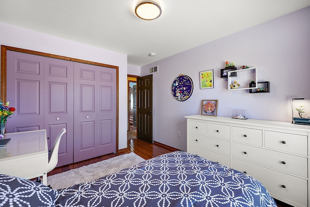 bedroom featuring baseboards, wood finished floors, visible vents, and a closet