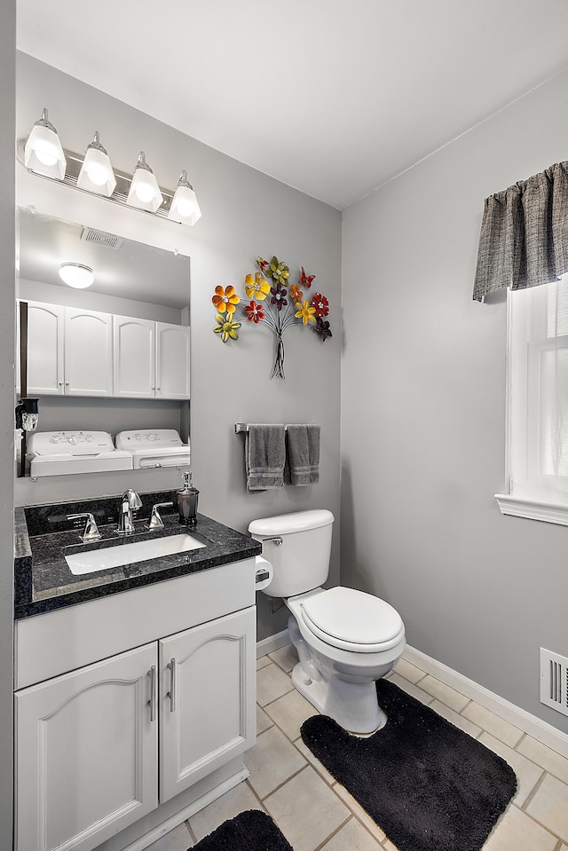 half bath featuring tile patterned floors, visible vents, and washer and clothes dryer