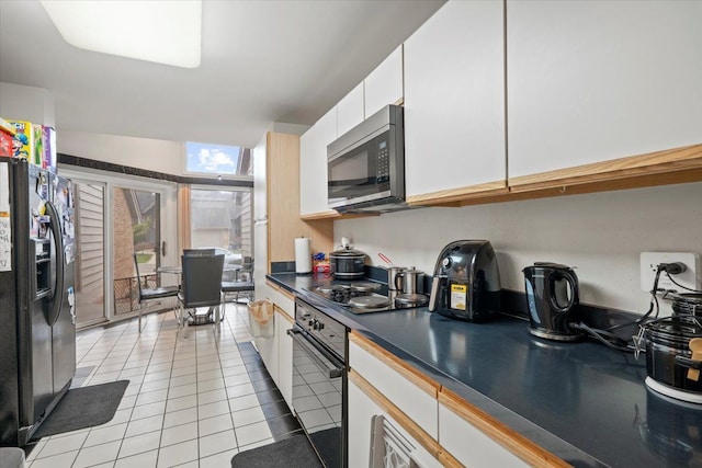 26765 Plumgrove Ln, Farmington Hills, MI 48334 - kitchen featuring dark countertops, light tile patterned floors, white cabinetry, and black appliances