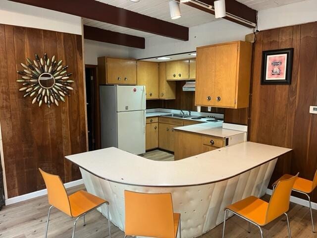 608 Terrace Dr, Houghton Lake, MI 48629 - kitchen featuring wooden walls, beamed ceiling, a peninsula, under cabinet range hood, and freestanding refrigerator