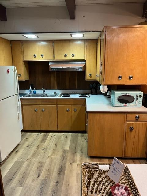 608 Terrace Dr, Houghton Lake, MI 48629 - kitchen featuring a sink, brown cabinets, white appliances, light wood-type flooring, and under cabinet range hood