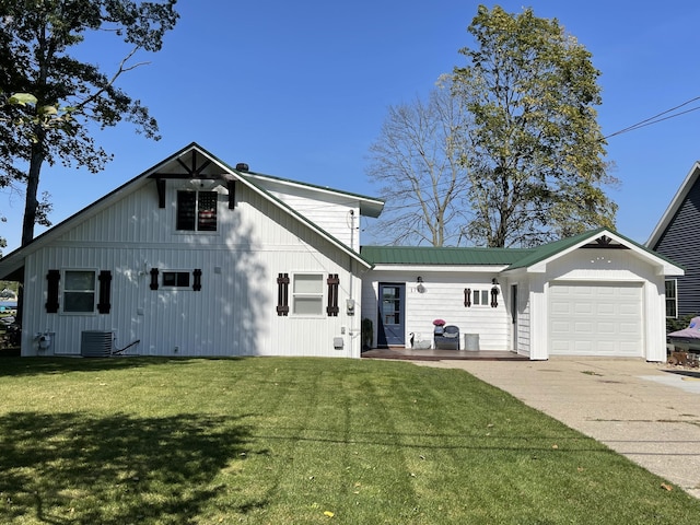 17570 Apache Trl, Howard City, MI 49329 - view of front facade featuring concrete driveway, central air condition unit, a front lawn, an attached garage, and metal roof