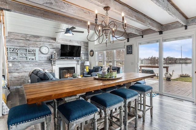 17570 Apache Trl, Howard City, MI 49329 - dining room featuring wooden walls, visible vents, beamed ceiling, wood-type flooring, and a glass covered fireplace