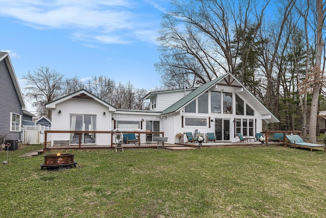 17570 Apache Trl, Howard City, MI 49329 - back of property featuring a fire pit, a sunroom, a deck, and a lawn