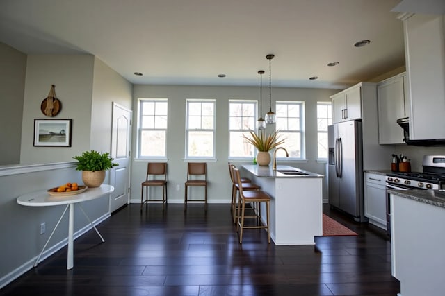 kitchen featuring appliances with stainless steel finishes, a kitchen breakfast bar, a sink, and a healthy amount of sunlight