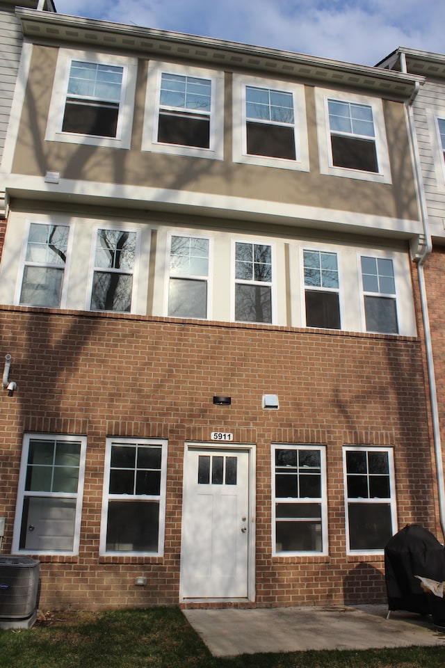 view of front of home featuring brick siding and central air condition unit