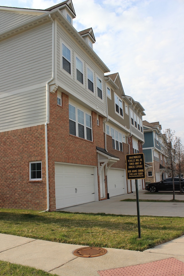 view of front of property with brick siding, a residential view, an attached garage, and driveway