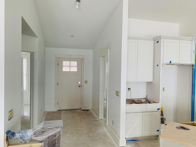 foyer featuring vaulted ceiling and baseboards