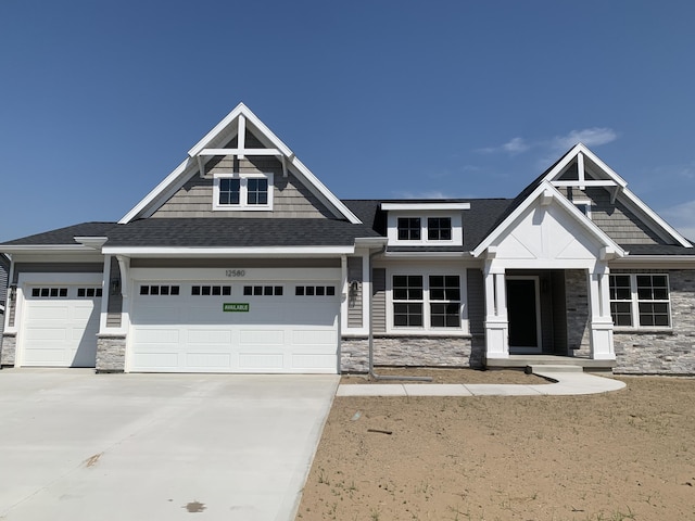 12580 Riverton Rd, Grand Haven, MI 49417 - craftsman-style home featuring stone siding, driveway, an attached garage, and roof with shingles
