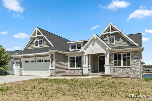 12580 Riverton Rd, Grand Haven, MI 49417 - craftsman-style home with stone siding, concrete driveway, roof with shingles, a front lawn, and a garage