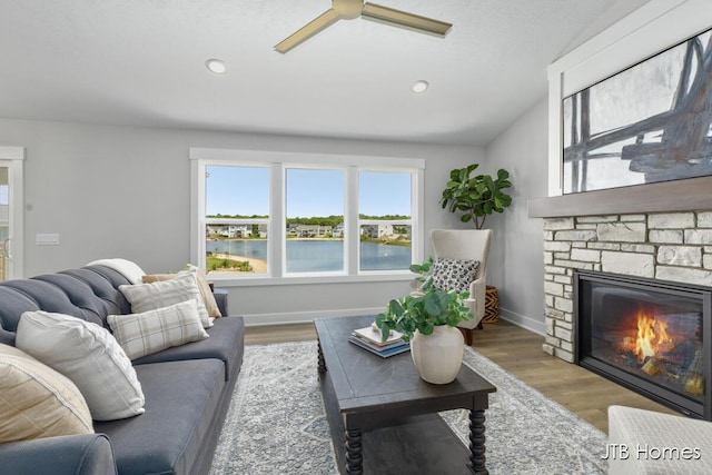 12580 Riverton Rd, Grand Haven, MI 49417 - living area with ceiling fan, a stone fireplace, wood finished floors, a water view, and lofted ceiling