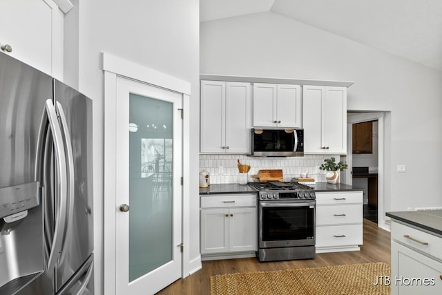 12580 Riverton Rd, Grand Haven, MI 49417 - kitchen with stainless steel appliances, dark countertops, lofted ceiling, decorative backsplash, and dark wood-type flooring