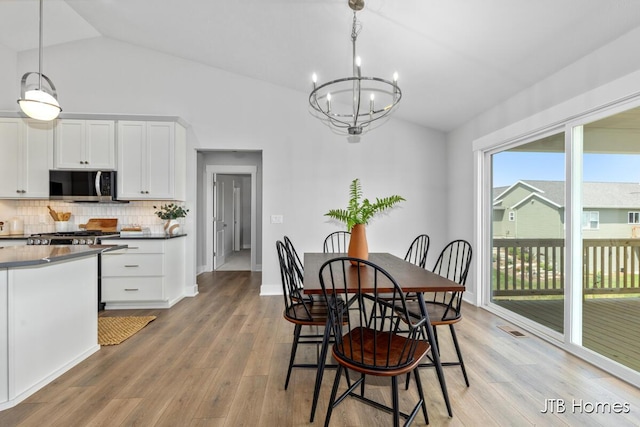12580 Riverton Rd, Grand Haven, MI 49417 - dining area with lofted ceiling, a chandelier, and light wood-type flooring