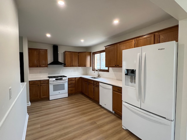 kitchen with decorative backsplash, light countertops, white appliances, and wall chimney range hood