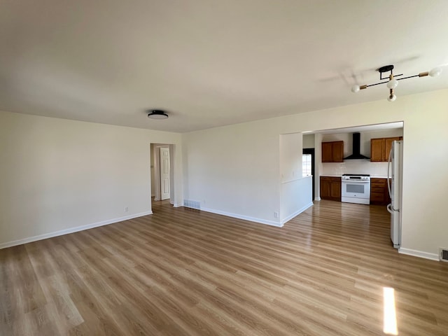 unfurnished living room with light wood finished floors, baseboards, and visible vents