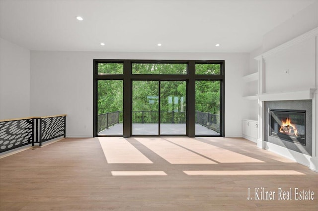 9465 Wabasis Pointe Dr NE, Greenville, MI 48838 - unfurnished living room with wood finished floors, a glass covered fireplace, recessed lighting, and baseboards