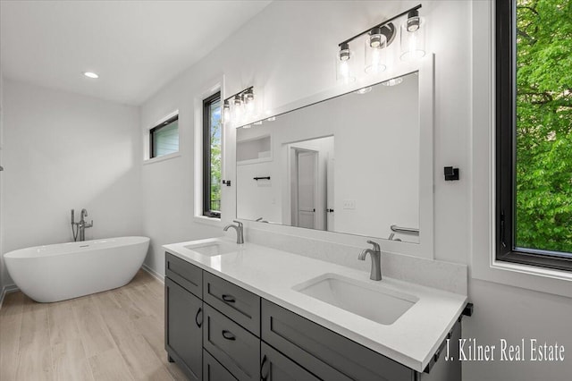 9465 Wabasis Pointe Dr NE, Greenville, MI 48838 - bathroom with double vanity, a freestanding bath, wood finished floors, and recessed lighting