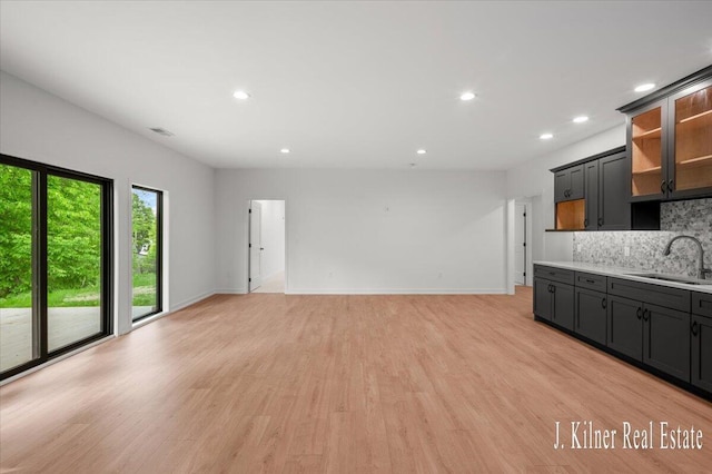 9465 Wabasis Pointe Dr NE, Greenville, MI 48838 - unfurnished living room featuring a sink, recessed lighting, light wood-style floors, and baseboards