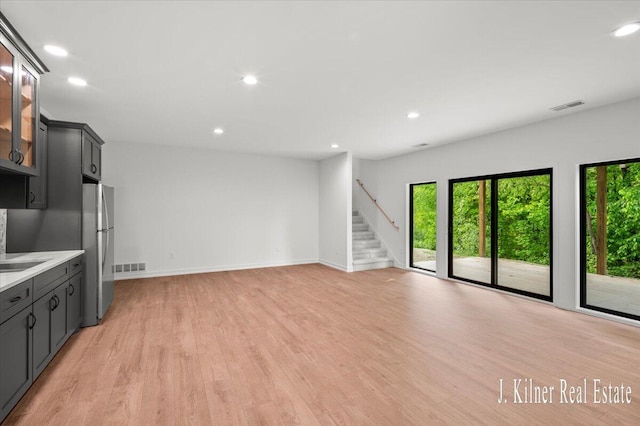 9465 Wabasis Pointe Dr NE, Greenville, MI 48838 - unfurnished living room with healthy amount of natural light, stairway, light wood finished floors, baseboards, and recessed lighting