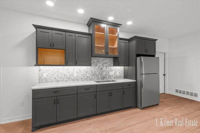 9465 Wabasis Pointe Dr NE, Greenville, MI 48838 - kitchen featuring freestanding refrigerator, a sink, tasteful backsplash, and light wood-style floors