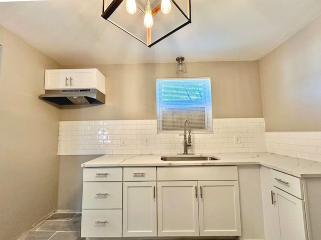10342 Britain St, Detroit, MI 48224 - kitchen with tasteful backsplash, light stone countertops, under cabinet range hood, white cabinets, and a sink