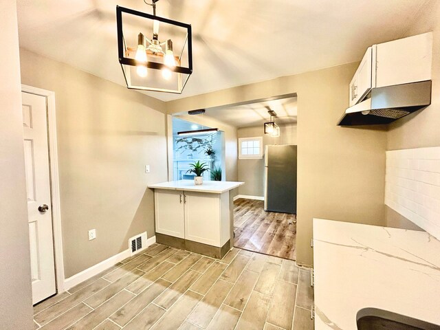 10342 Britain St, Detroit, MI 48224 - kitchen with white cabinetry, visible vents, freestanding refrigerator, and light wood-type flooring