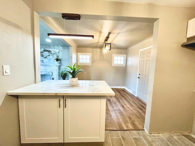 10342 Britain St, Detroit, MI 48224 - kitchen featuring wood finished floors, light stone countertops, white cabinetry, and baseboards