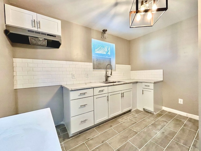 10342 Britain St, Detroit, MI 48224 - kitchen with under cabinet range hood, light countertops, white cabinets, backsplash, and a sink