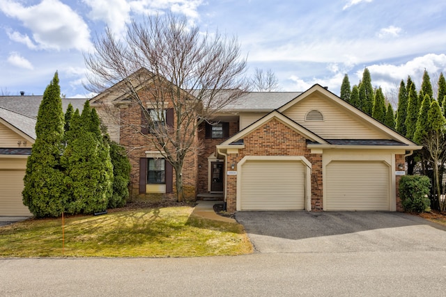 view of front facade featuring a front lawn, roof with shingles, driveway, brick siding, and a garage