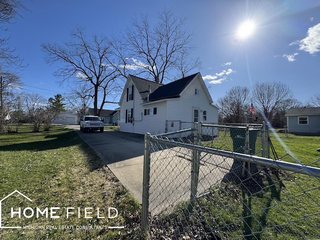 view of property exterior with fence, a lawn, and driveway