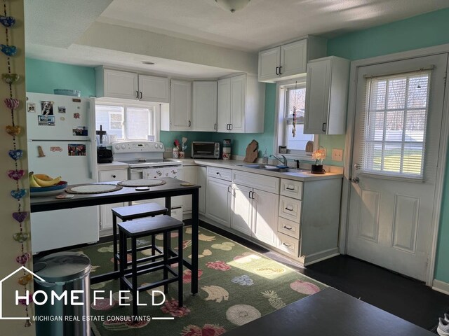 kitchen featuring a toaster, a sink, white cabinetry, white appliances, and light countertops