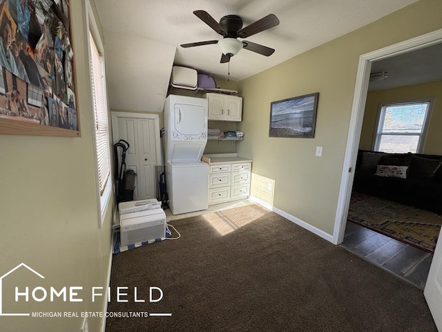 interior space with carpet, stacked washing maching and dryer, baseboards, cabinet space, and ceiling fan