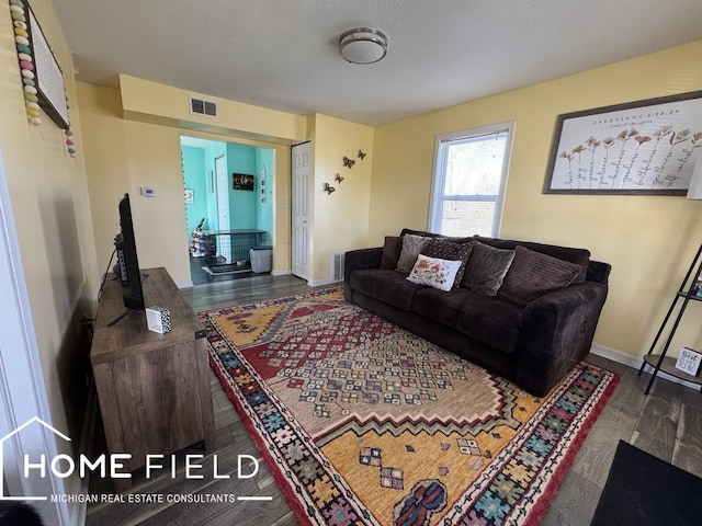 living room featuring wood finished floors, visible vents, and baseboards
