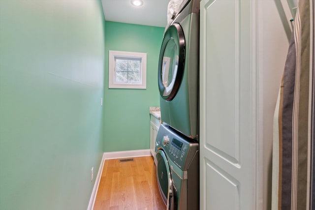 17867 K-Line Way, Marshall, MI 49068 - clothes washing area with visible vents, stacked washing maching and dryer, light wood-type flooring, baseboards, and cabinet space