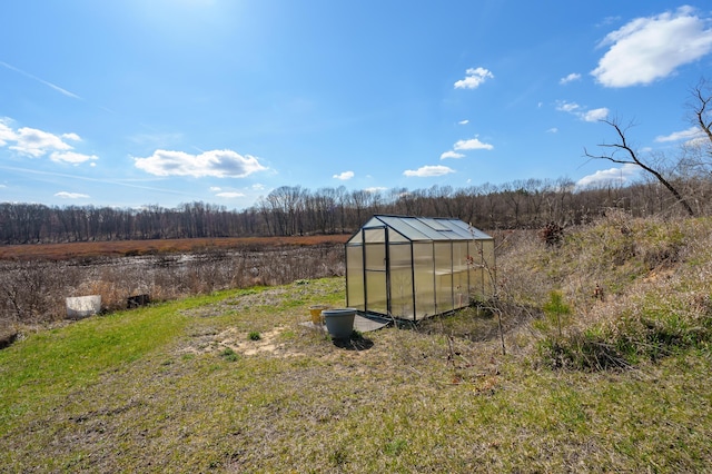 view of yard with an exterior structure, a wooded view, and an outdoor structure
