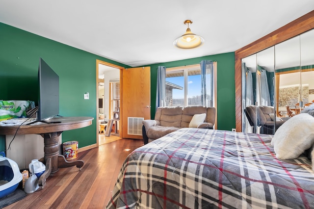 bedroom featuring baseboards, wood finished floors, visible vents, and a closet